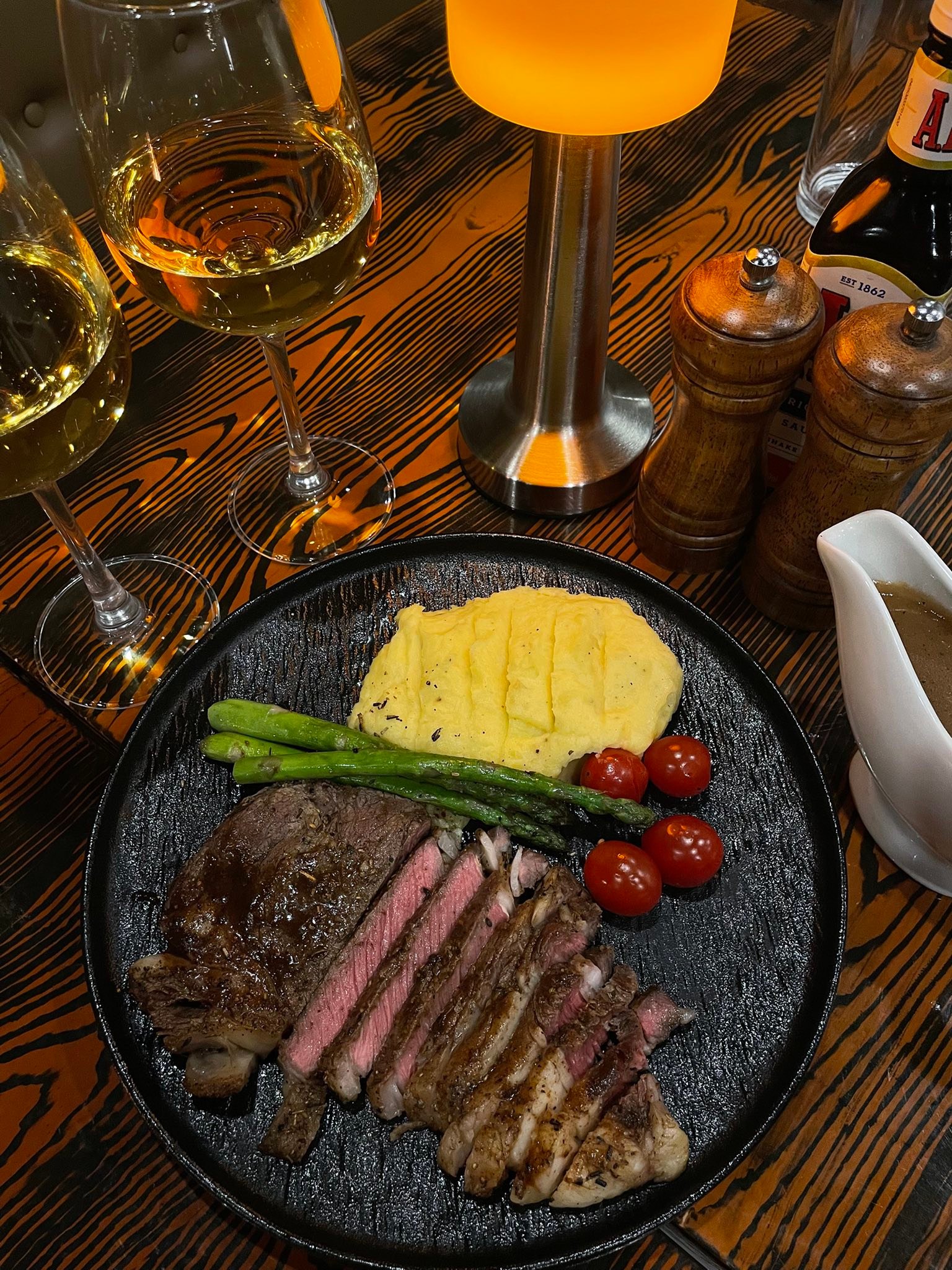 Lola's signature steak on cast iron skillet with mashed potato and asparagus — premium mains